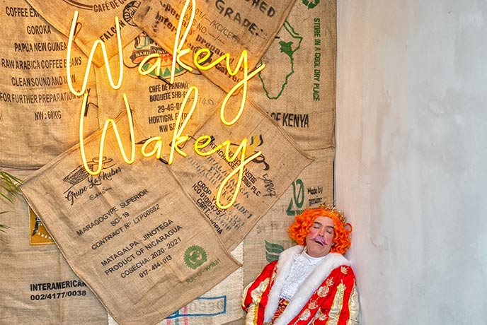 Someone in pantomime costume asleep against a wall that reads "wakey wakey" at Theatre Royal Wakefield